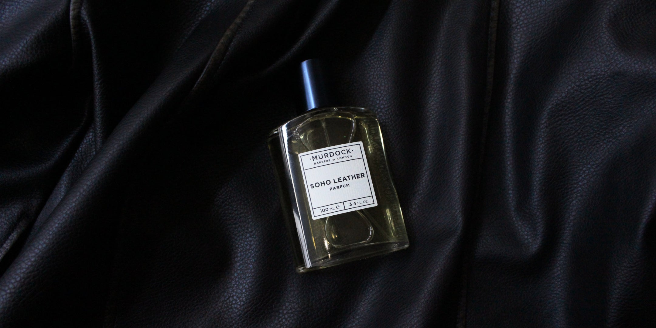A bottle of Murdock London Soho Leather perfume placed on a draped black leather surface.