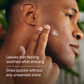 Close-up of a man's face and hand applying or smoothing a white cream onto his cheek, with overlaid text reading 'Leaves skin feeling soothed after shaving' and 'Dries quickly without any unwanted shine'.