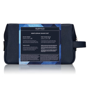 A dark navy blue Murdock London gentleman's shave set pouch with a large blue and black product information label wrapped around the front, shown on a white background with a soft reflection.