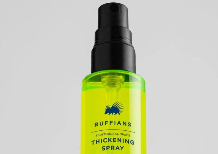 A bottle of Ruffians Thickening Spray with a black spray nozzle and a translucent neon yellow-green bottle, shown against a light gray background.